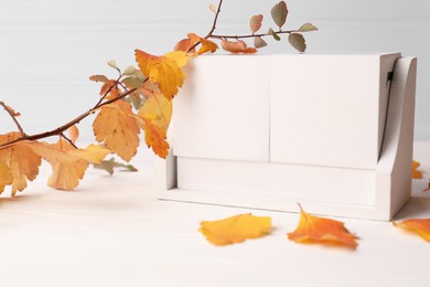 Photo of Thanksgiving day, holiday celebrated every fourth Thursday in November. Block calendar and branch with orange leaves on white wooden table