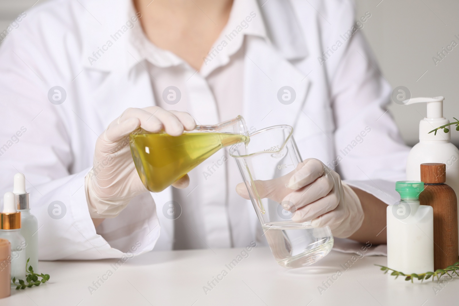 Photo of Dermatologist developing cosmetic product at white table indoors, selective focus