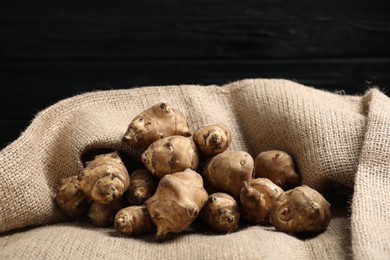 Photo of Jerusalem artichokes on bag against dark background