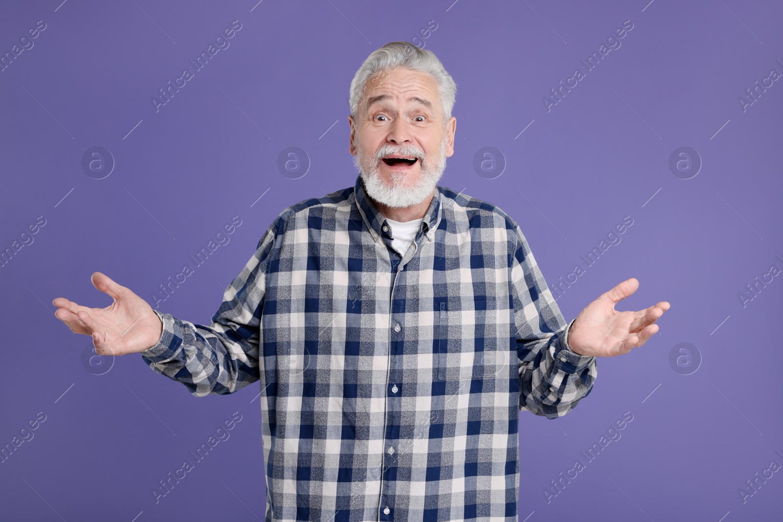 Photo of Portrait of surprised senior man on violet background