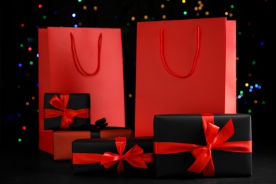 Photo of Paper shopping bags and gift boxes against blurred lights. Black Friday sale