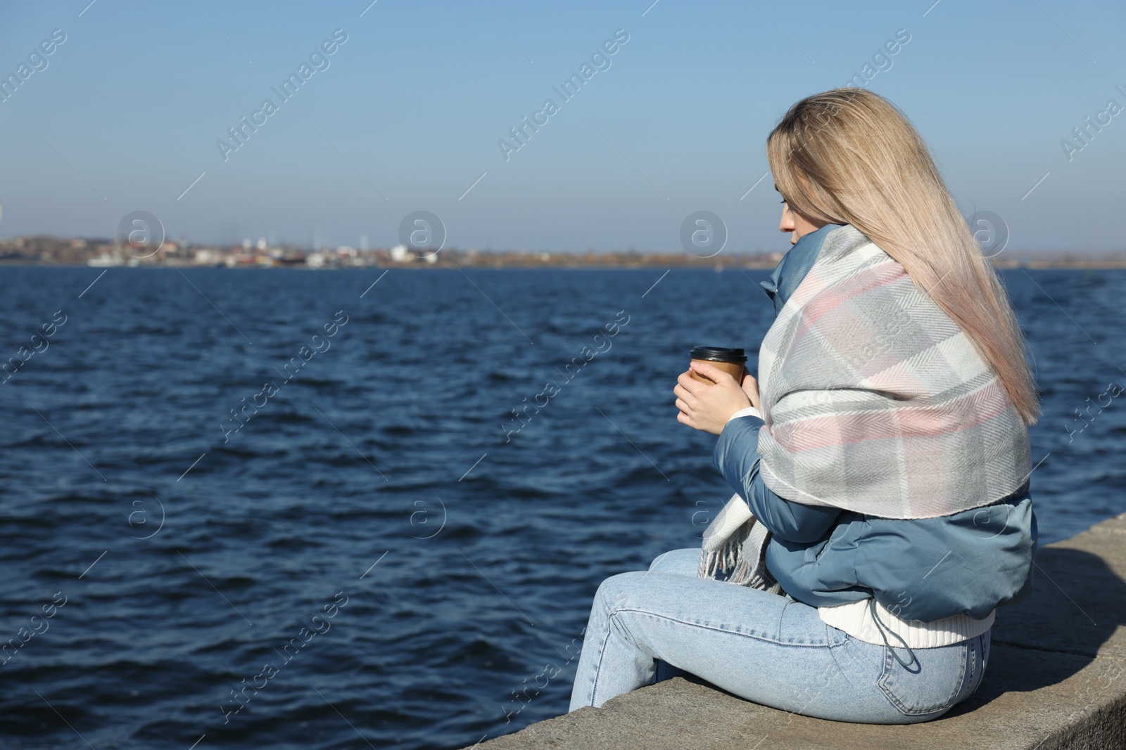 Photo of Lonely woman with cup of drink near river on sunny day