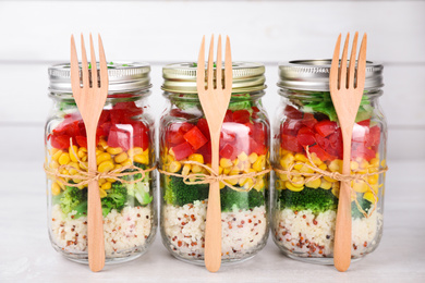 Photo of Glass jars with healthy meal on white wooden table