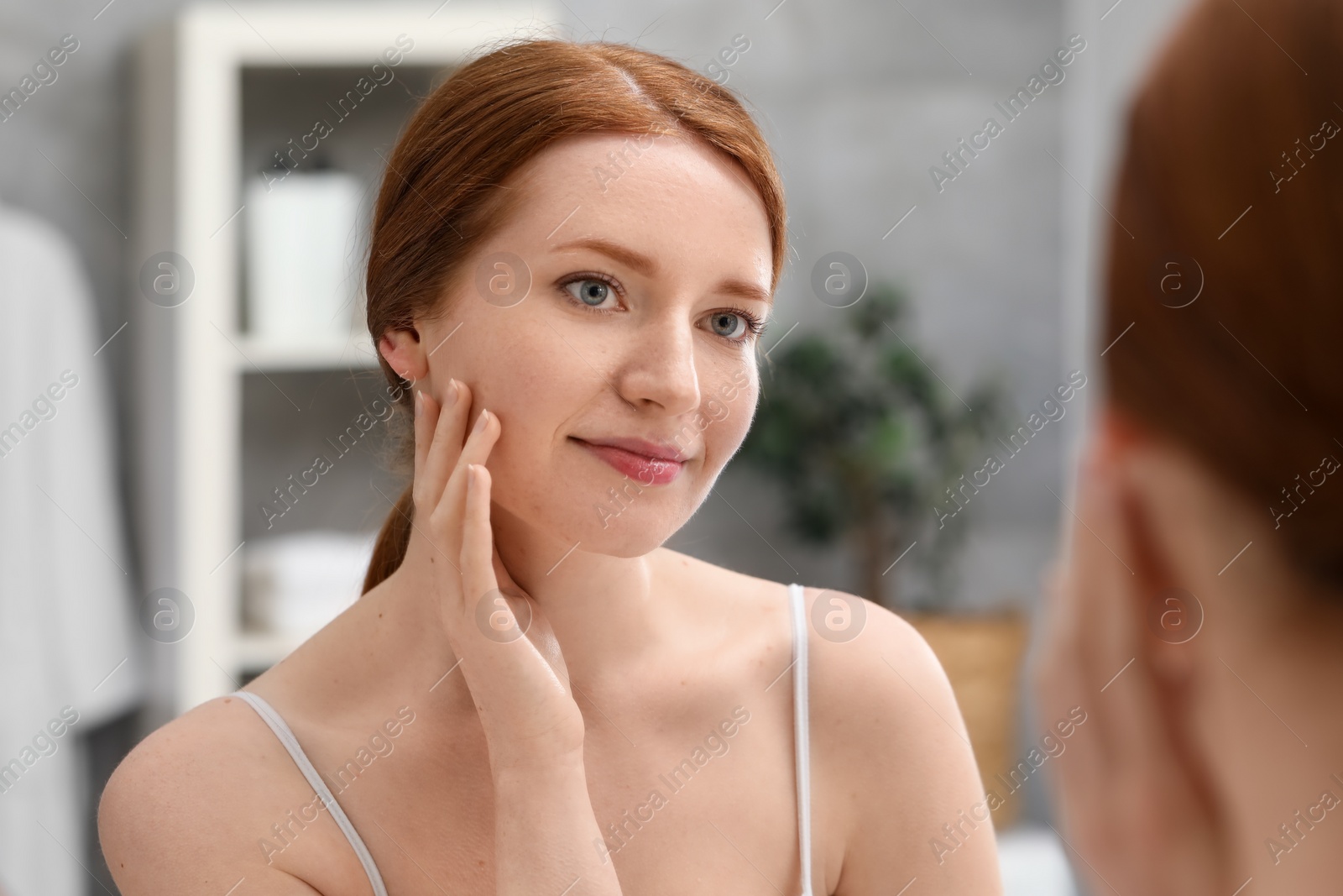 Photo of Beautiful woman with freckles near mirror in bathroom