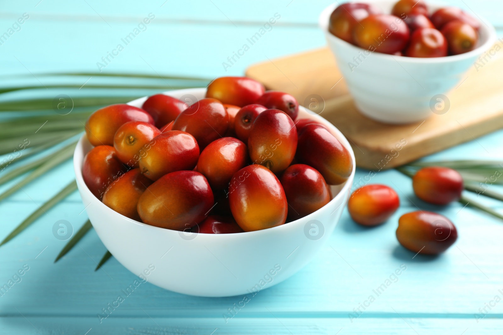 Photo of Palm oil fruits in bowl on turquoise wooden table, closeup