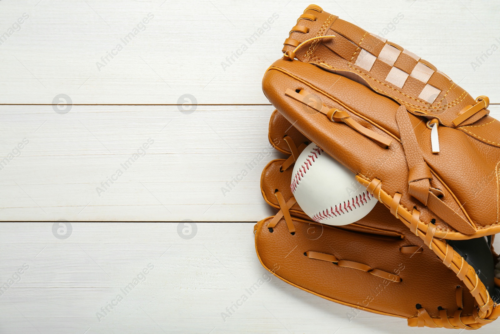 Photo of Leather baseball glove with ball on white wooden table, top view. Space for text