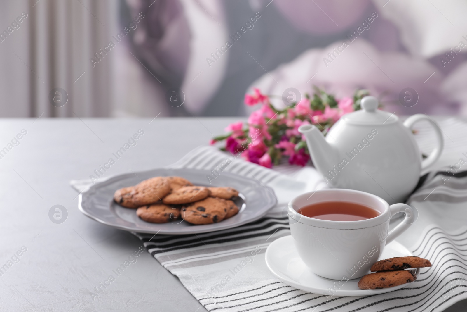 Photo of Cup of aromatic tea and tasty cookies on grey table