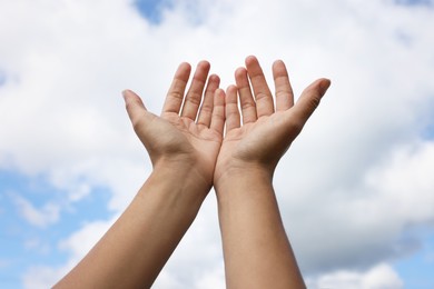 Photo of Woman reaching hands to blue sky outdoors on sunny day, closeup