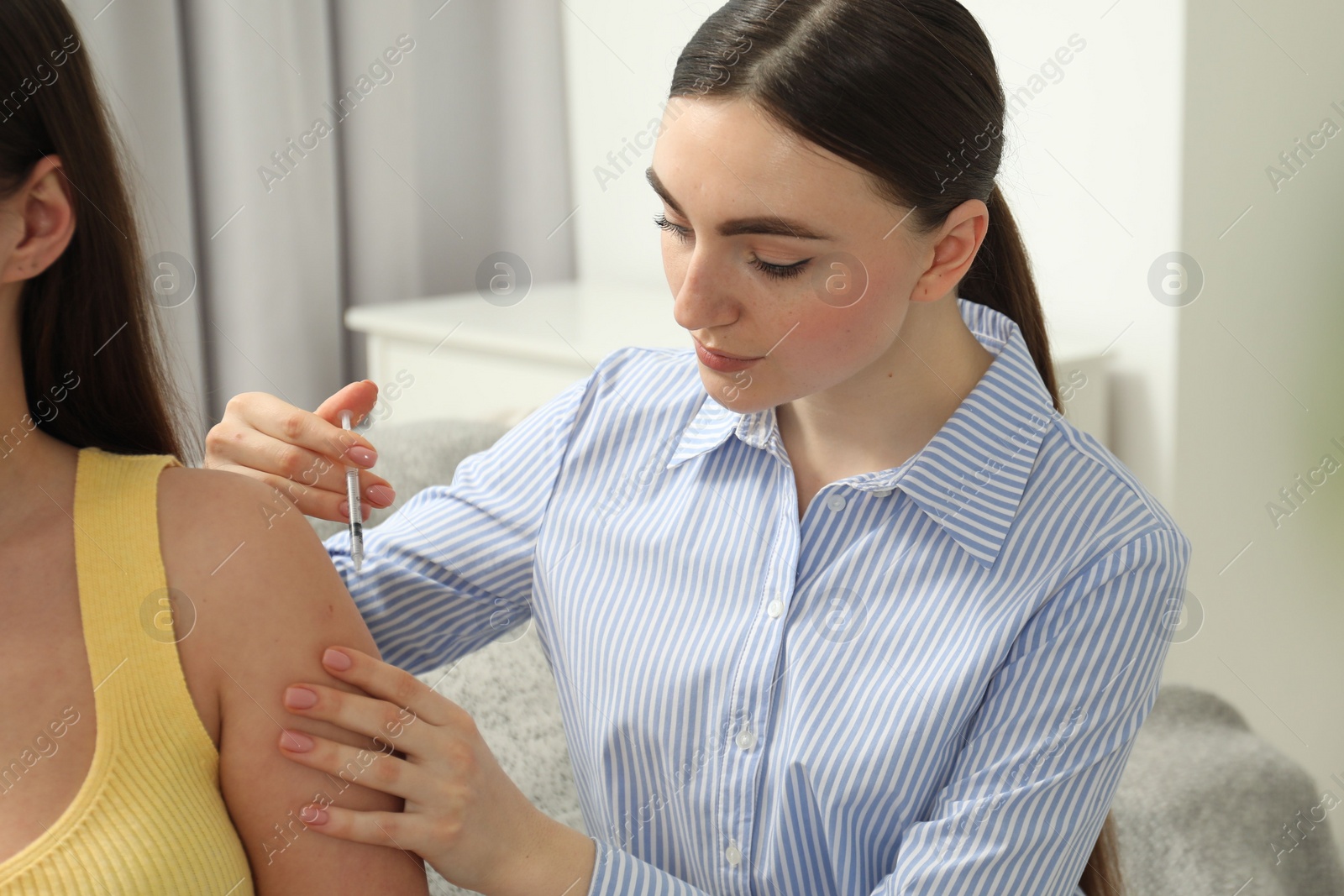 Photo of Woman giving insulin injection to her diabetic friend at home