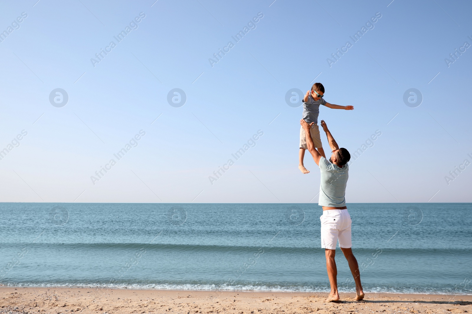 Photo of Father playing with son at beach. Family vacation