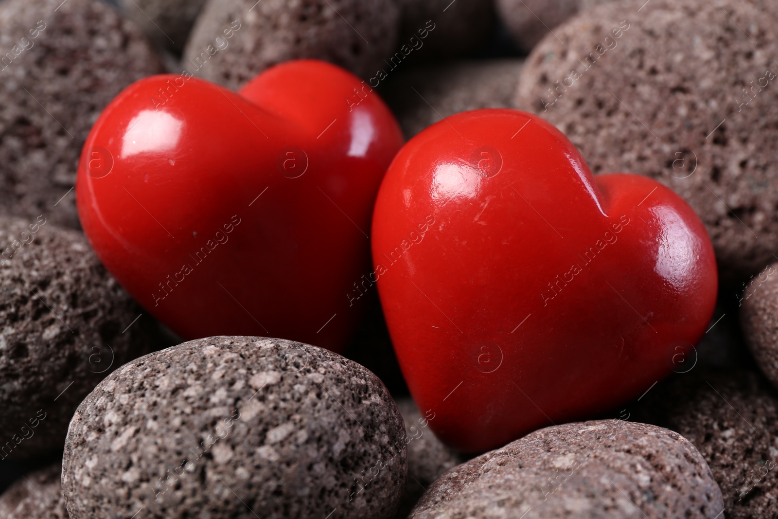 Photo of Red decorative hearts on stones, closeup view