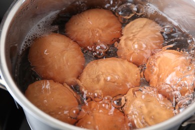 Chicken eggs boiling in pot, closeup view