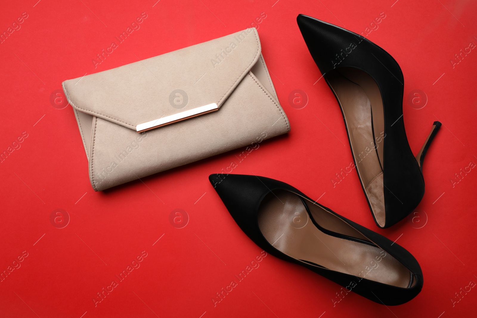 Photo of Pair of elegant high heel shoes and handbag on red background, flat lay