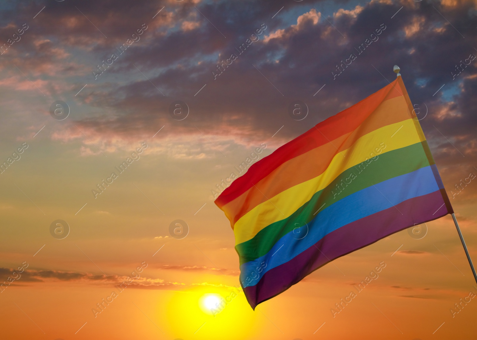 Image of Bright rainbow LGBT flag against sky at sunset