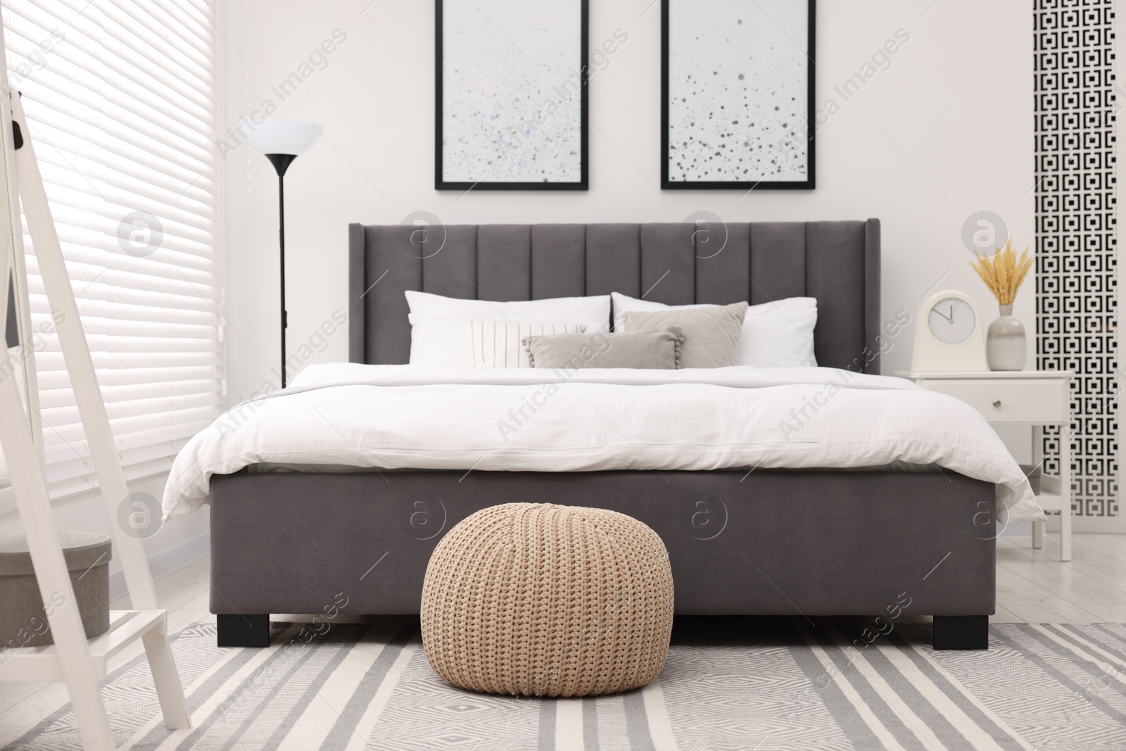 Photo of Stylish bedroom interior with large bed, bedside table and lamp