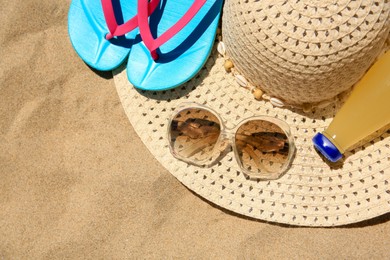 Photo of Straw hat, sunglasses, flip flops and refreshing drink on sand, above view. Beach accessories