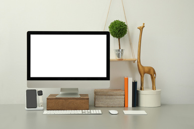 Photo of Modern workplace with computer, charging devices and decor elements. Interior design