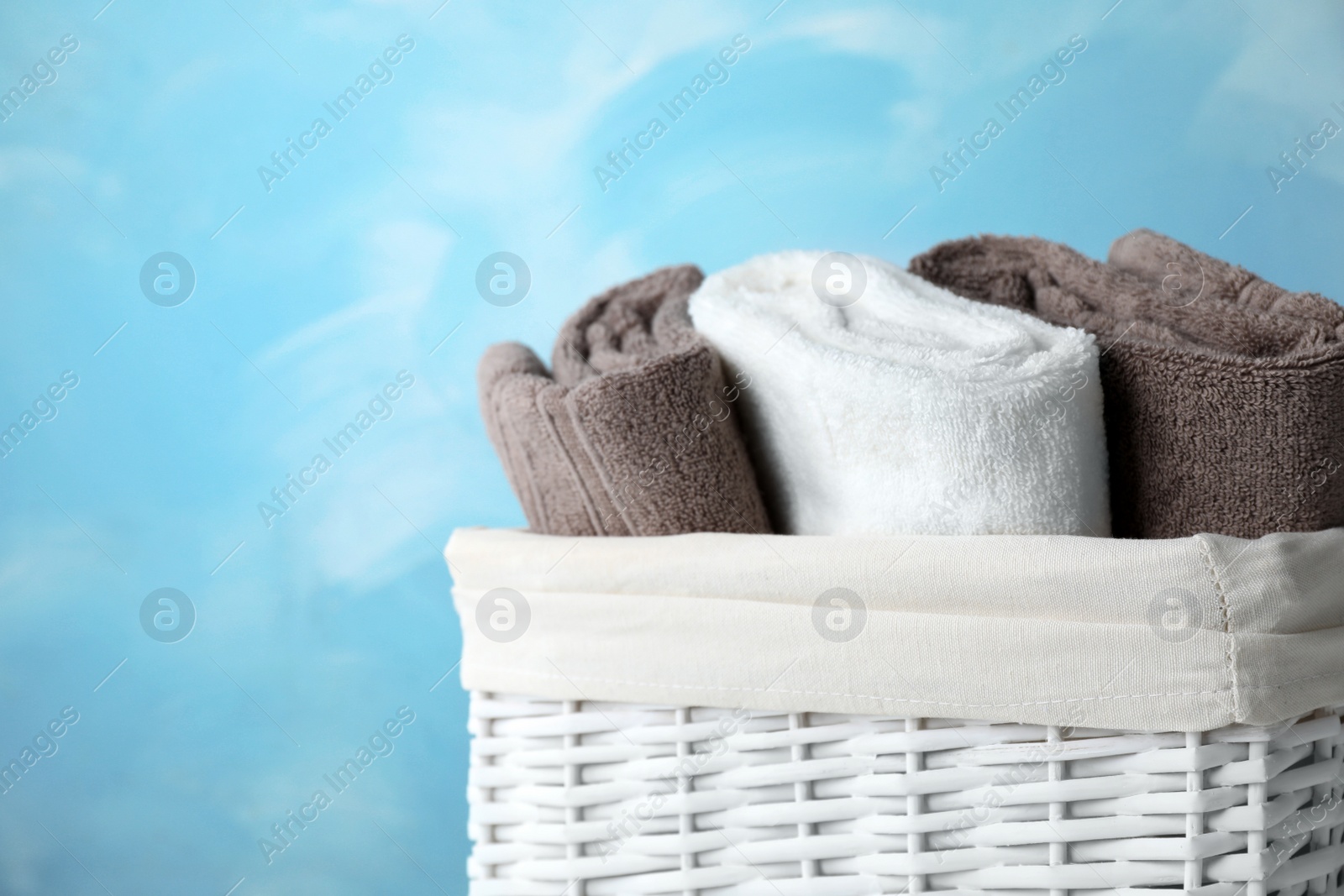 Photo of Basket with soft bath towels on color background. Space for text