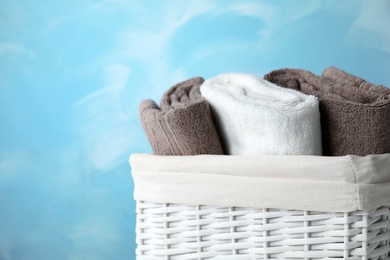 Basket with soft bath towels on color background. Space for text