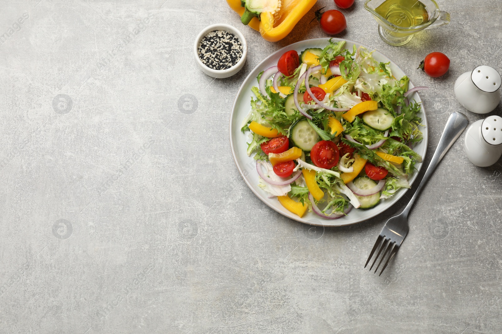 Photo of Tasty fresh vegetarian salad and fork on grey table, flat lay. Space for text