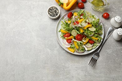 Photo of Tasty fresh vegetarian salad and fork on grey table, flat lay. Space for text