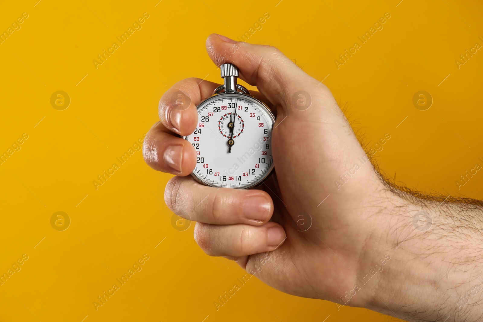 Photo of Man holding vintage timer on yellow background, closeup