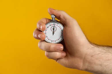 Man holding vintage timer on yellow background, closeup