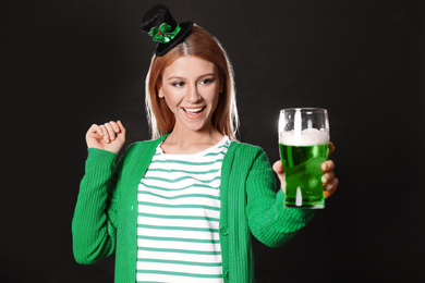 Young woman with green beer on black background. St. Patrick's Day celebration