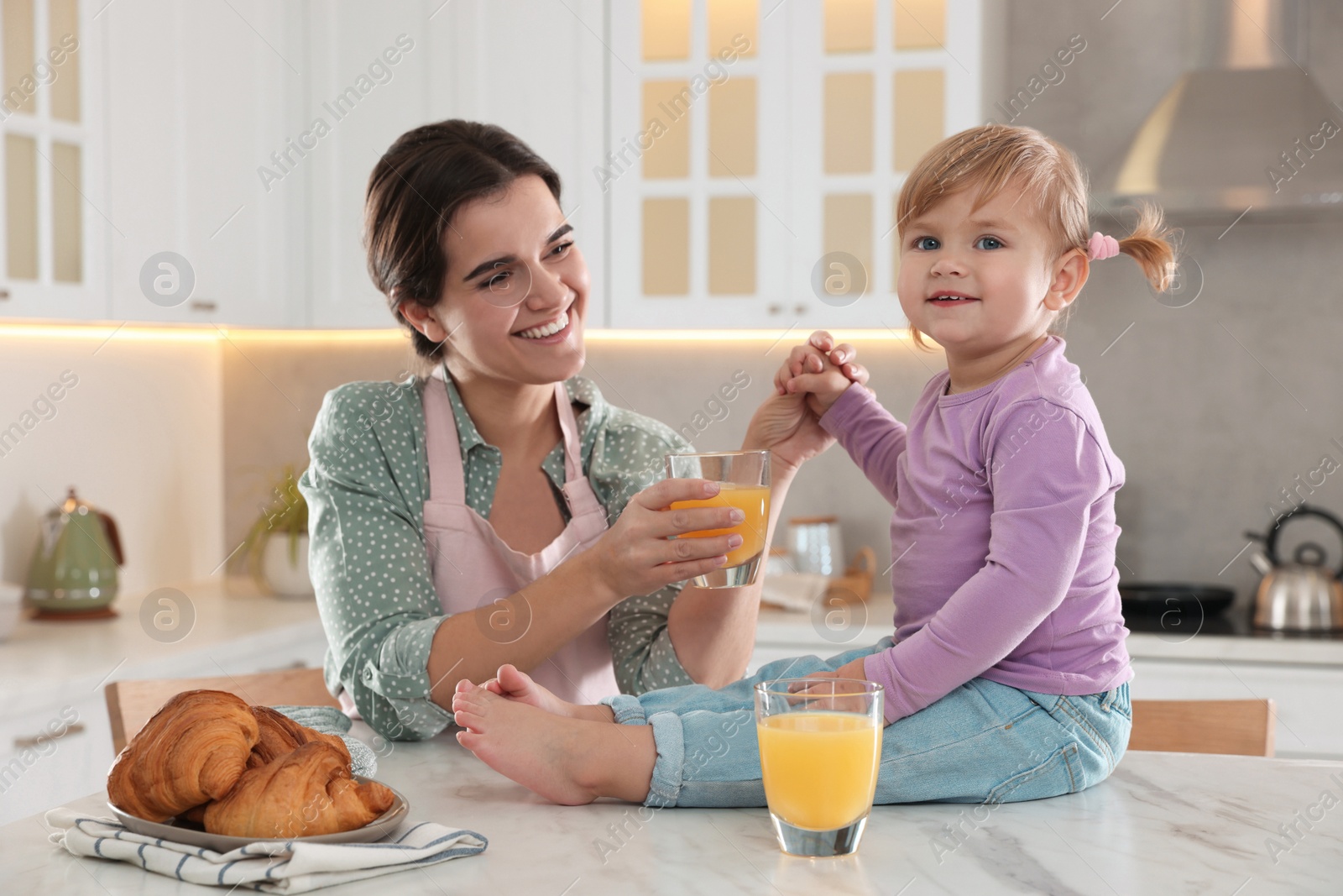 Photo of Mother and her little daughter having breakfast together in kitchen