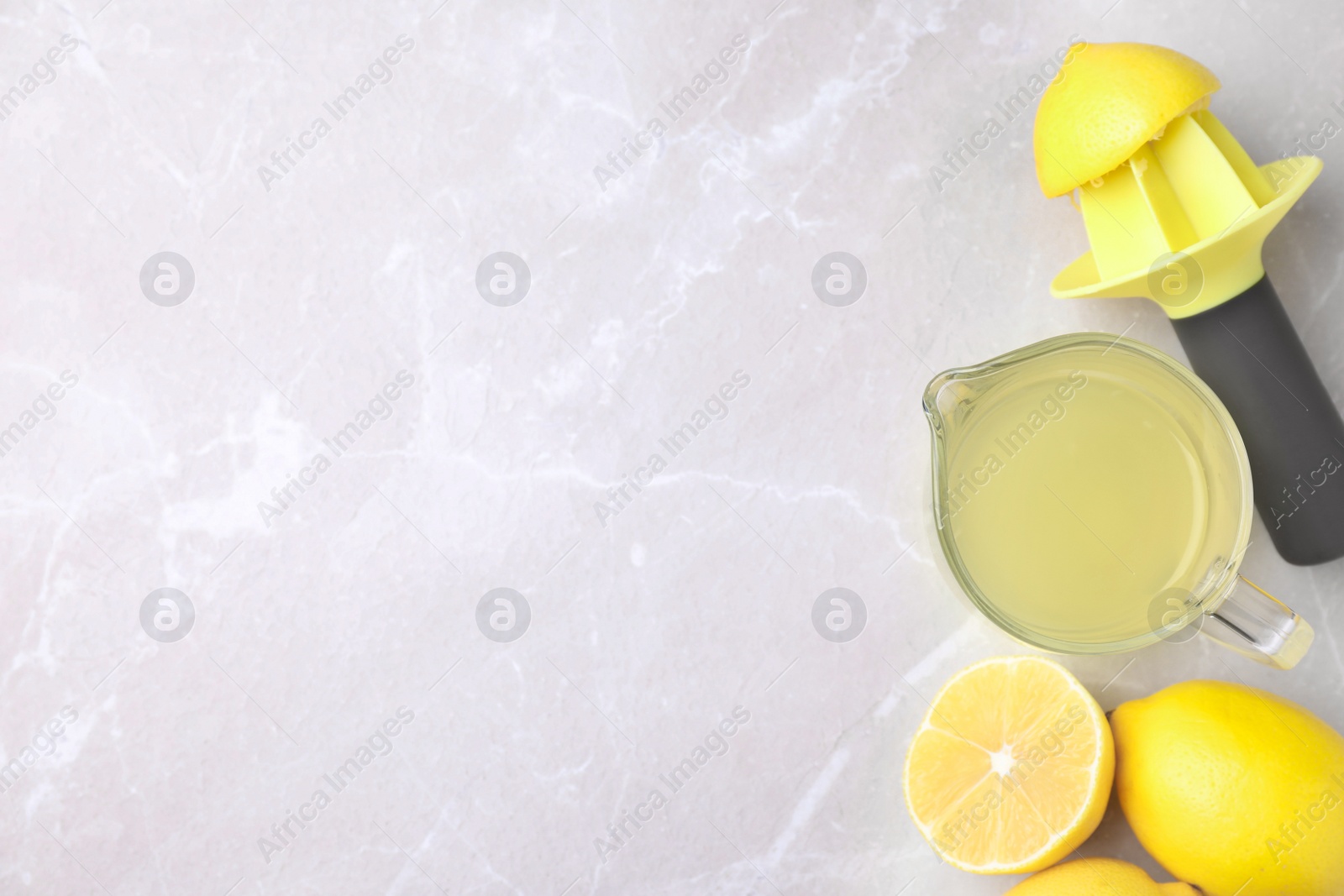 Photo of Flat lay composition with freshly squeezed lemon juice on light table. Space for text