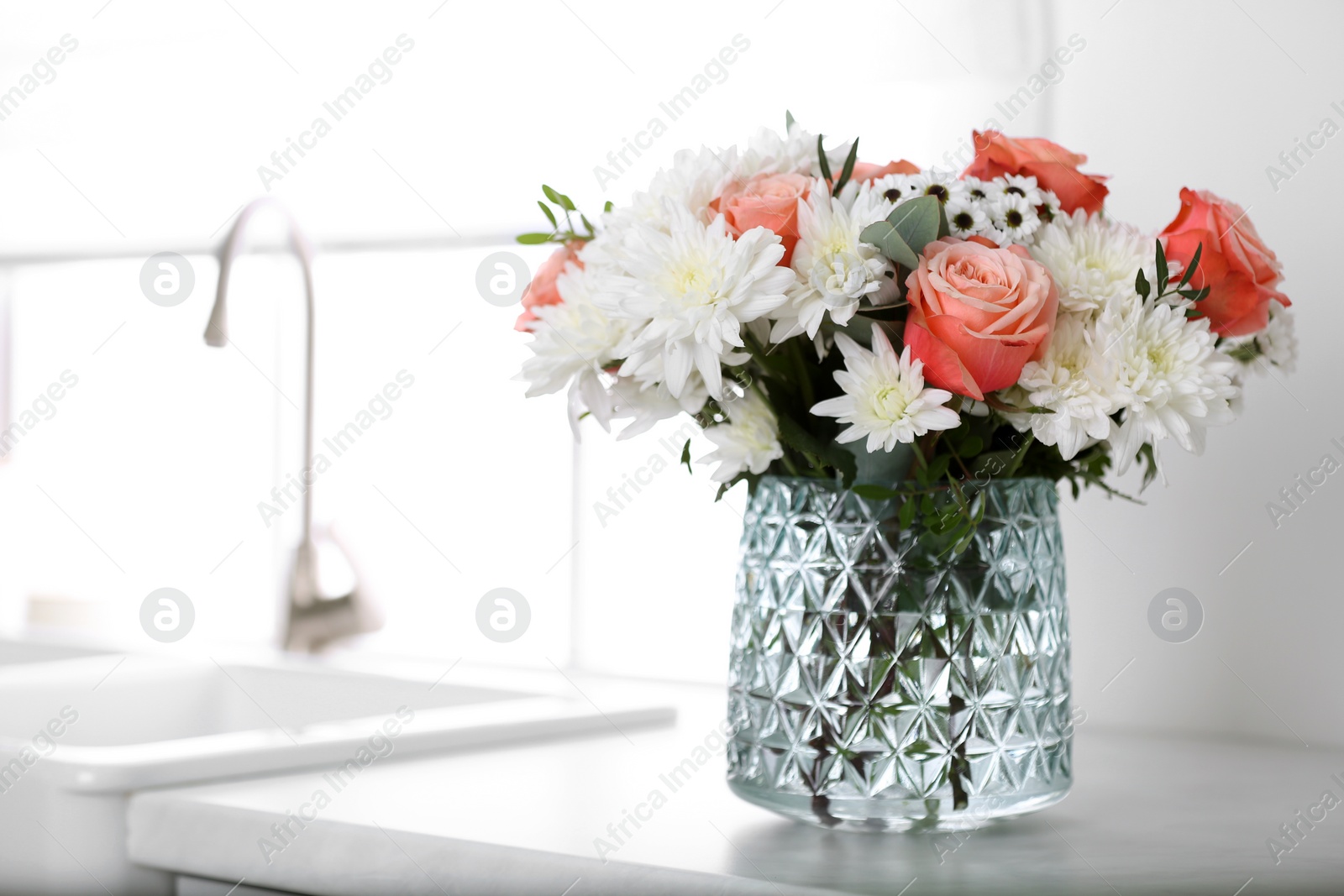 Photo of Vase with beautiful flowers on countertop in kitchen, space for text. Interior design