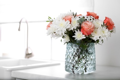 Photo of Vase with beautiful flowers on countertop in kitchen, space for text. Interior design