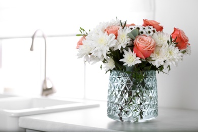 Vase with beautiful flowers on countertop in kitchen, space for text. Interior design