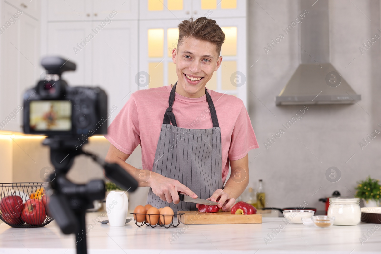 Photo of Smiling food blogger cooking while recording video in kitchen