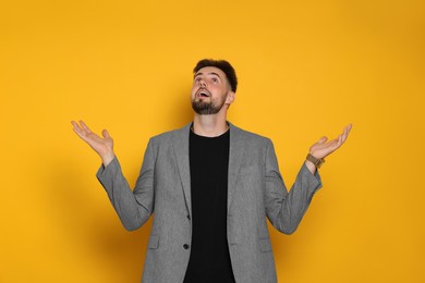 Photo of Surprised man in stylish grey jacket on yellow background