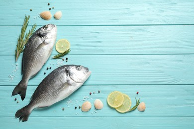 Flat lay composition with raw dorada fish on light blue wooden table, space for text