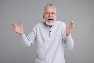 Photo of Portrait of surprised senior man on grey background