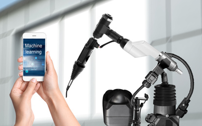 Image of Engineer controlling electronic laboratory robot manipulator with smartphone indoors, closeup. Machine learning