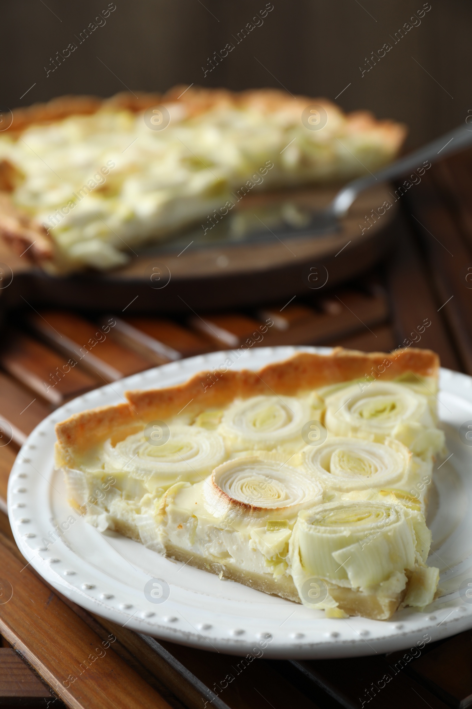Photo of Plate with piece of tasty leek pie on wooden table, closeup