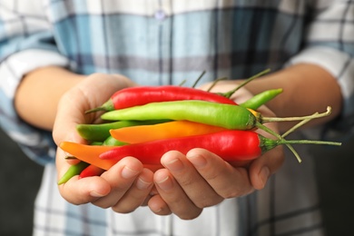 Photo of Young woman holding different hot chili peppers, closeup