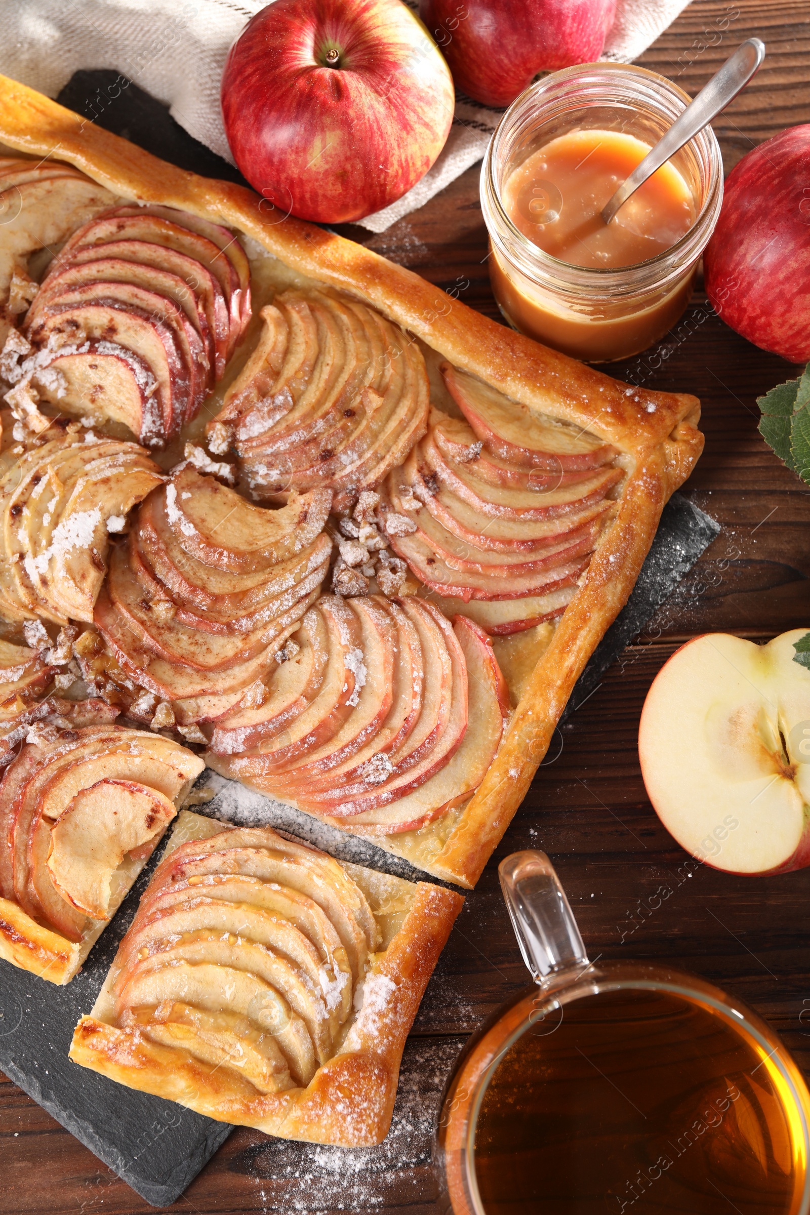 Photo of Freshly baked apple pie served with tea on wooden table, flat lay