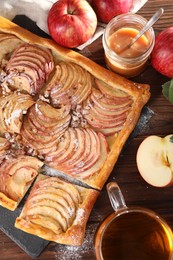 Photo of Freshly baked apple pie served with tea on wooden table, flat lay