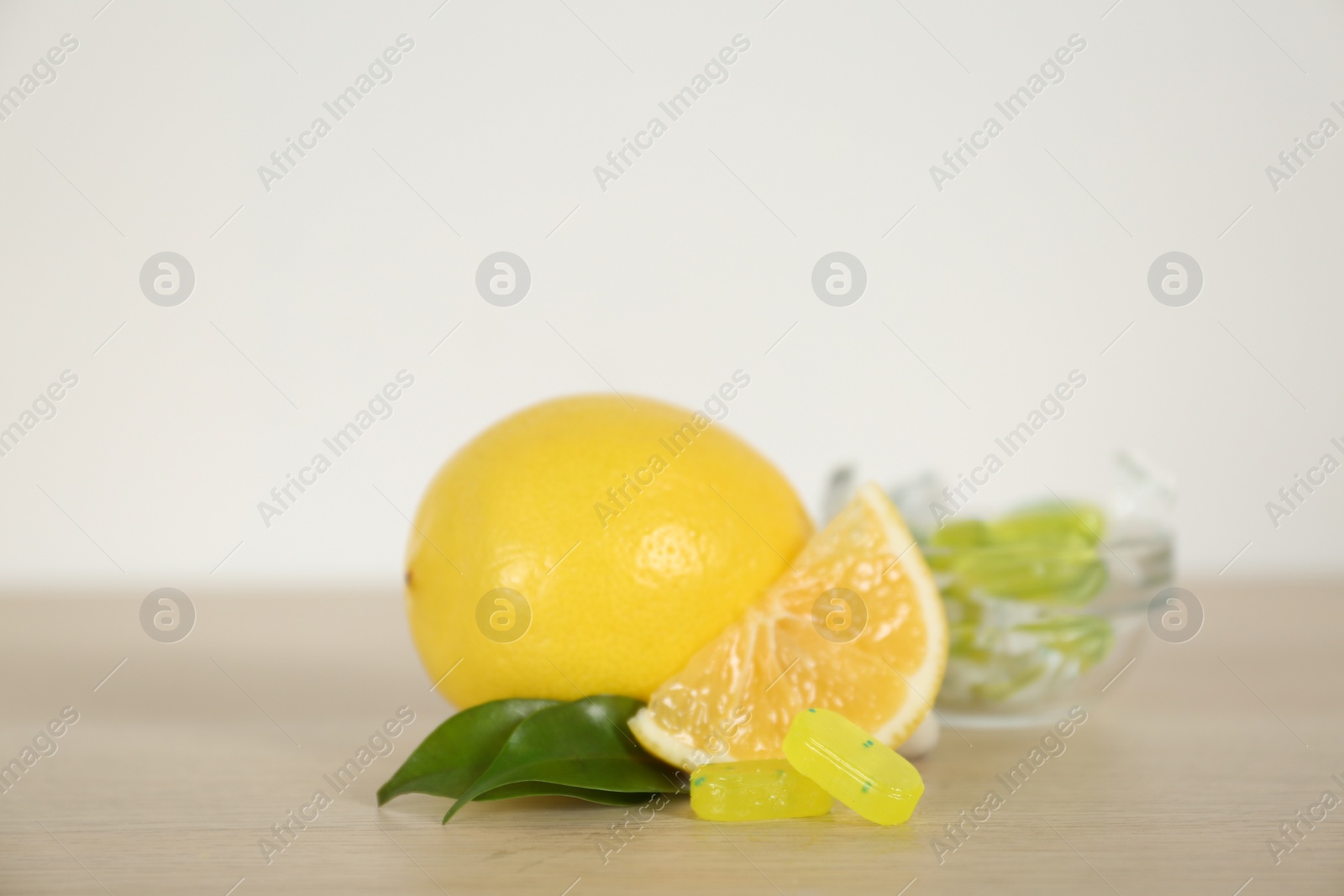 Photo of Fresh lemon and tasty small drops on wooden table