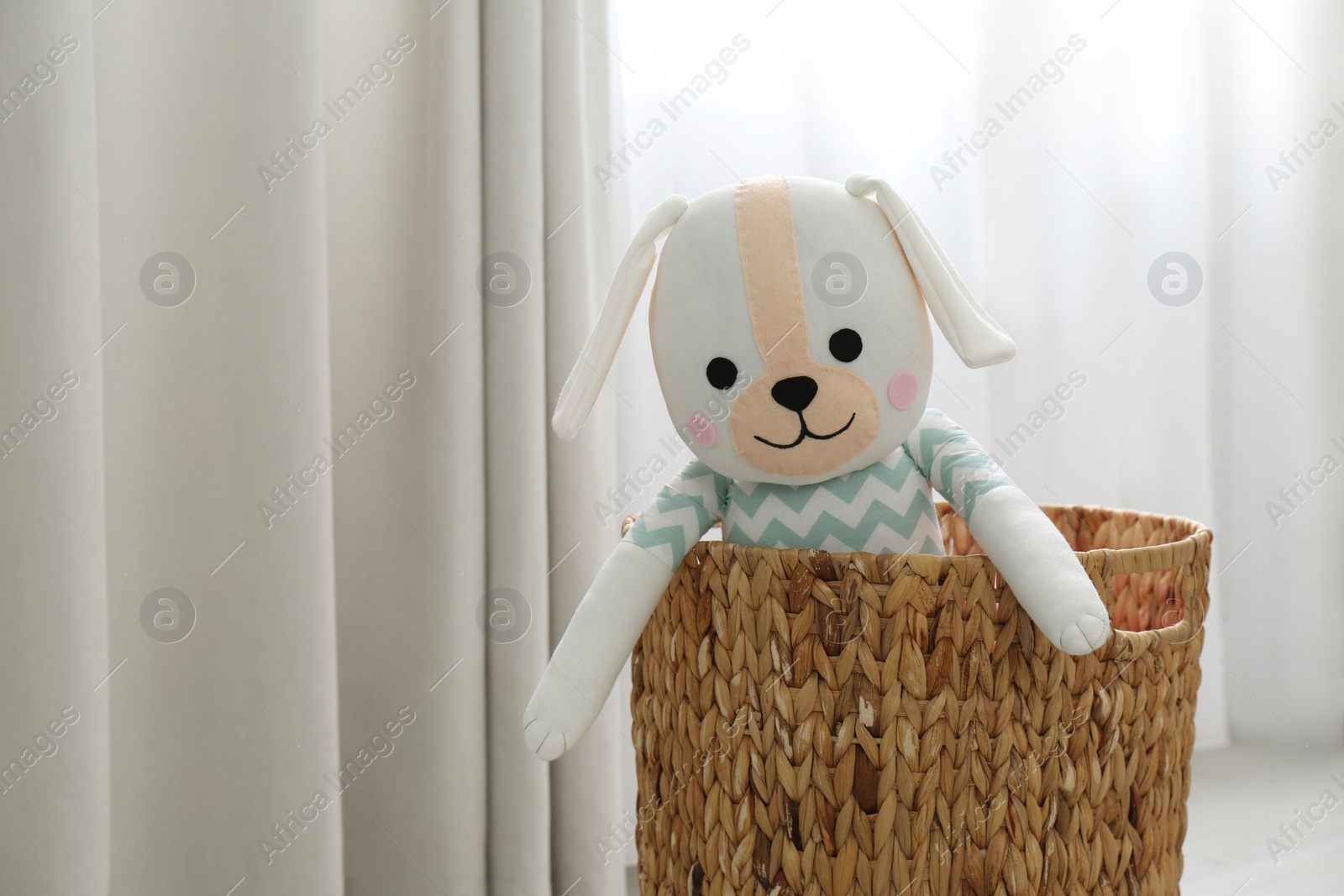 Photo of Funny toy dog in basket near window. Decor for children's room interior