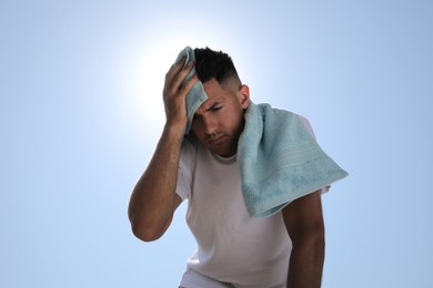 Man with towel suffering from heat stroke outdoors, low angle view