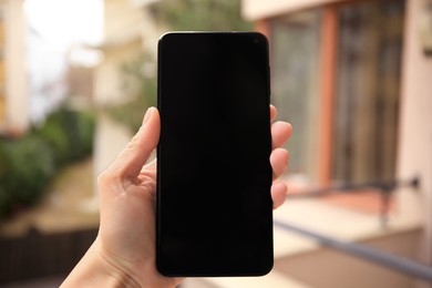 Photo of Woman holding smartphone with blank screen outdoors, closeup
