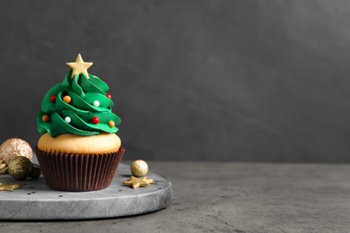 Photo of Christmas tree shaped cupcake on grey table. Space for text