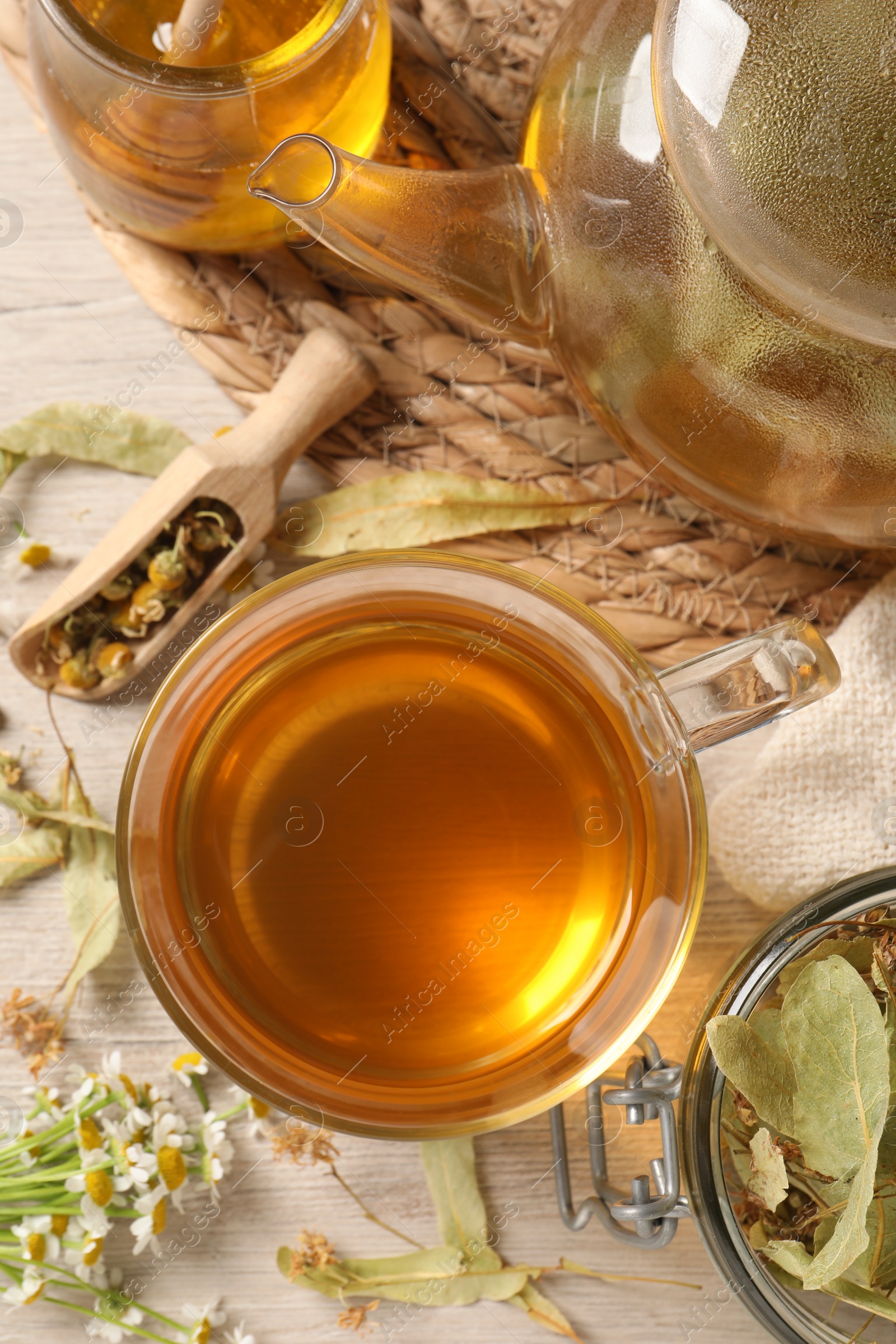 Photo of Freshly brewed tea, honey and dried herbs on white wooden table, flat lay