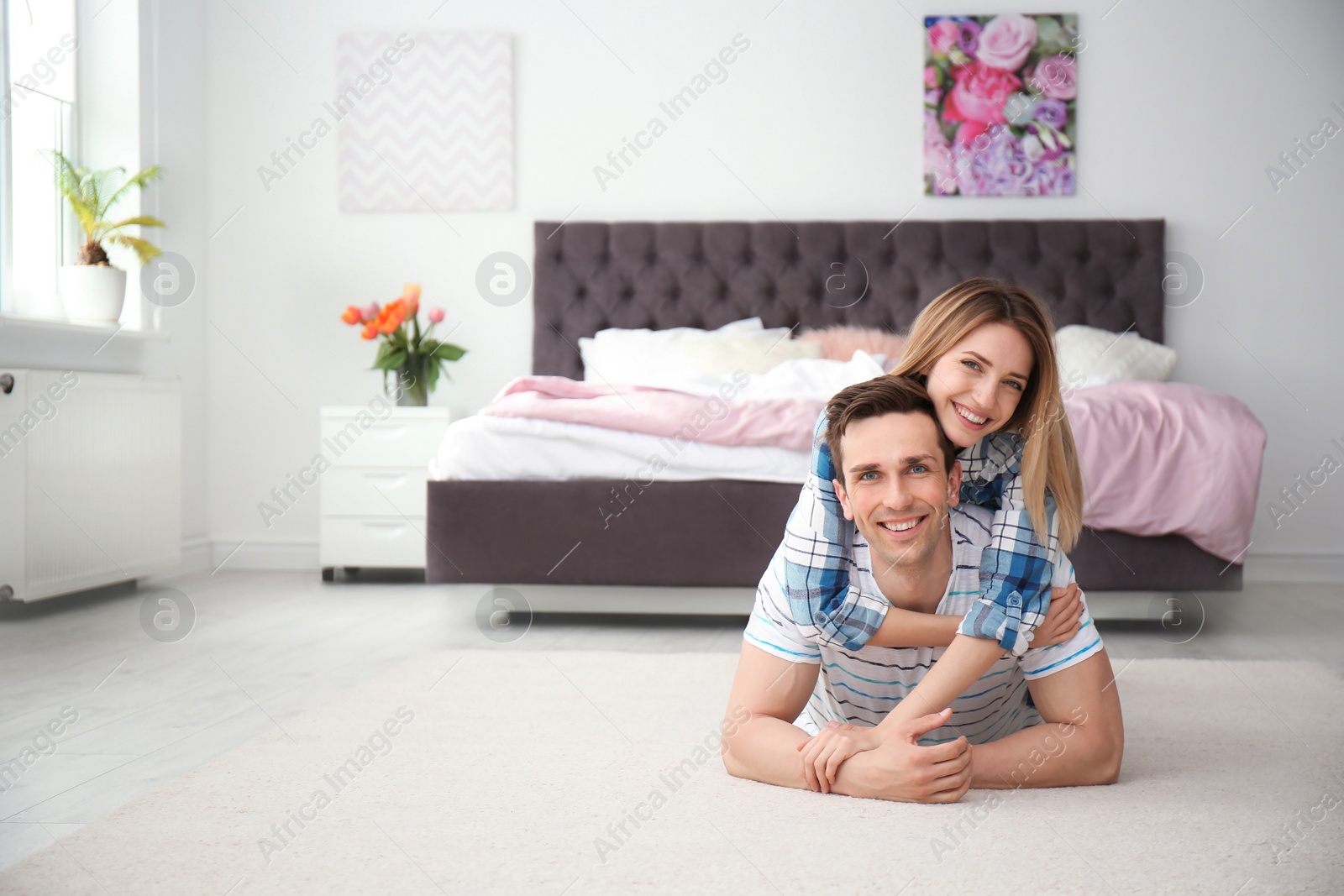 Photo of Lovely young couple lying on cozy carpet at home