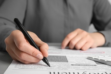 Woman marking advertisement in newspaper, closeup. Job search concept